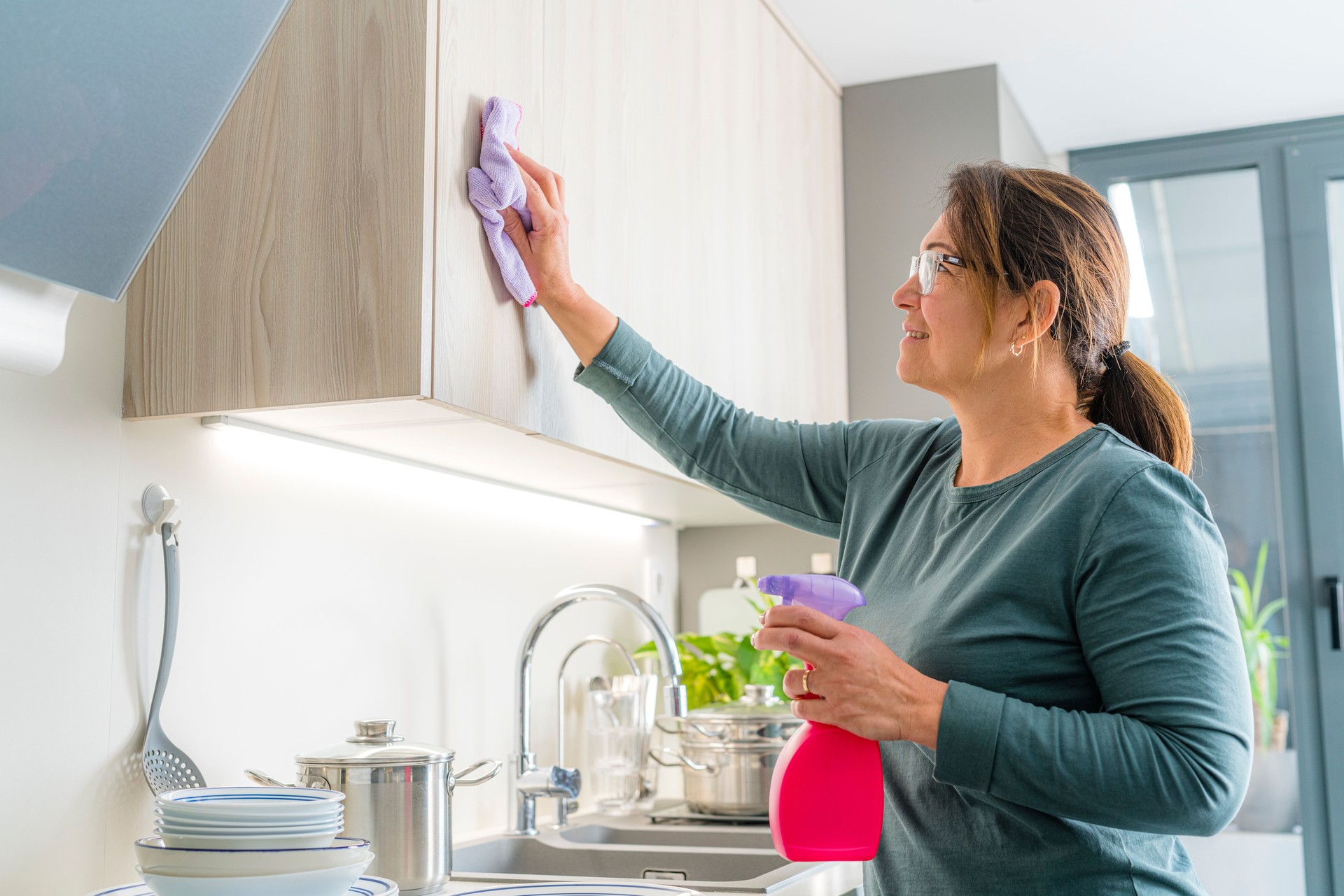 Woman cleaning kitchen cabinets